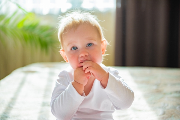 Baby girl posing with hands near mouth