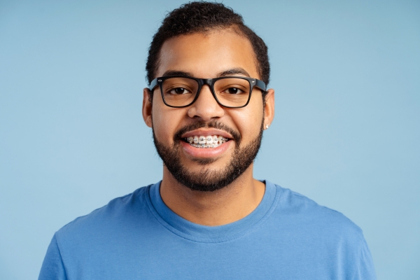 Man wearing glasses is smiling showing off his braces