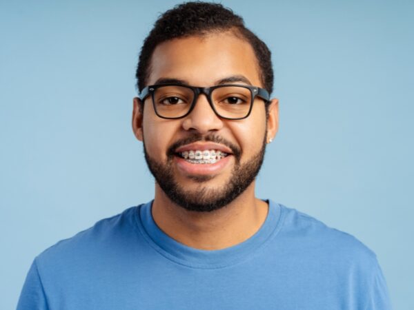 Young man wearing a blue shirt is smiling with braces on his teeth.